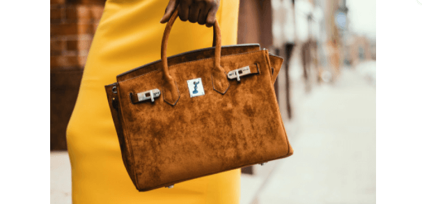 Woman in a yellow dress holding a brown leather tote bag